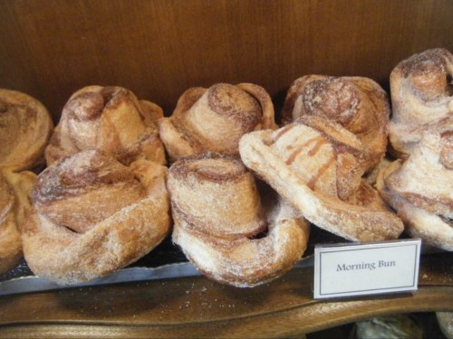 A display of freshly baked morning buns, resembling cinnamon rolls, dusted with sugar.