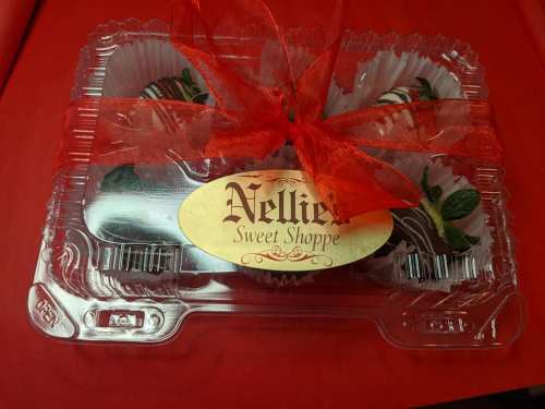 A clear plastic container with chocolate-covered strawberries, tied with a red ribbon and labeled "Nellie's Sweet Shoppe."