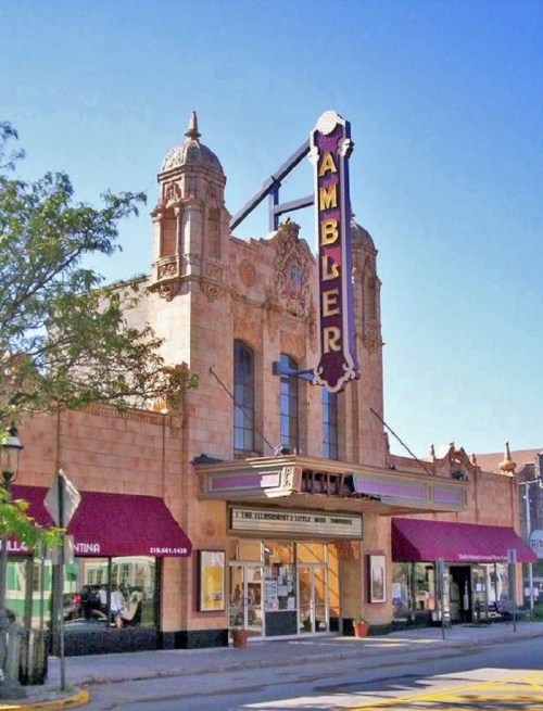 Historic Ambler Theater with ornate architecture and a vibrant marquee, set against a clear blue sky.