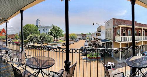 A panoramic view of a town square with parked cars, historic buildings, and trees under a clear blue sky.