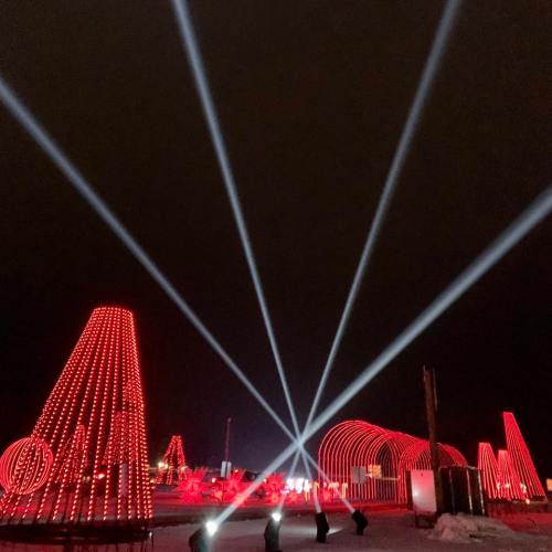 Bright red light installations with beams illuminating the night sky, creating a festive atmosphere.