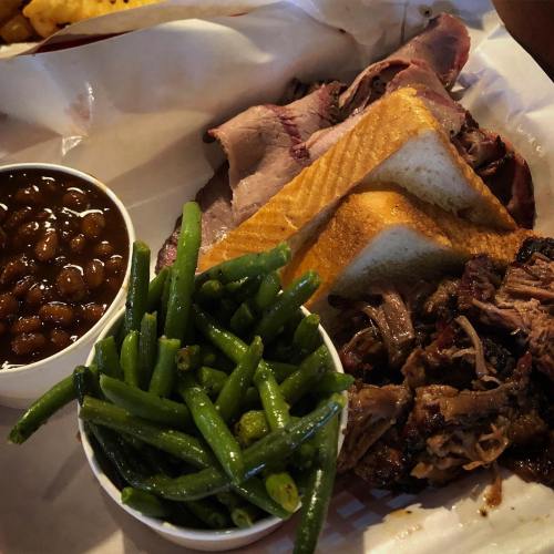A plate featuring pulled pork, green beans, baked beans, and slices of bread.