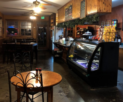 Cozy café interior with a display case, wooden tables, and a rustic atmosphere.
