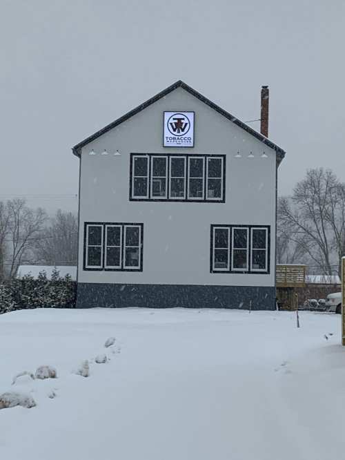 A snowy scene featuring a two-story building with a sign that reads "Topacco Co." on the front.