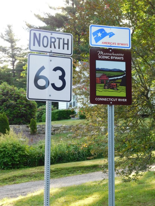 Road signs indicating North on Route 63 and a Scenic Byway sign for the Connecticut River in Massachusetts.