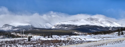 Snow-covered mountains under a blue sky with clouds, showcasing a serene winter landscape.