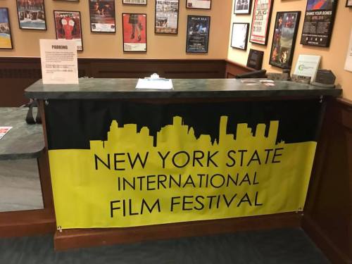 A banner for the New York State International Film Festival displayed at a reception desk.
