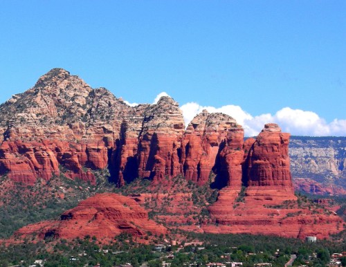 Red rock formations rise against a clear blue sky, showcasing the natural beauty of Sedona, Arizona.