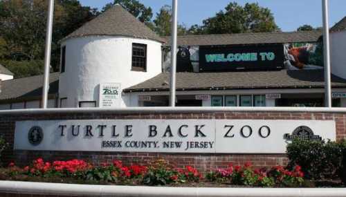 Entrance to Turtle Back Zoo in Essex County, New Jersey, featuring a welcome sign and colorful flower beds.