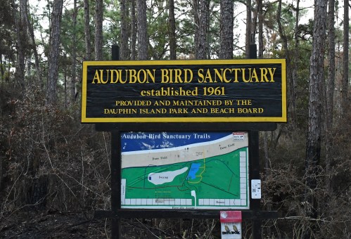 Sign for Audubon Bird Sanctuary, established in 1961, with a map of the trails and surrounded by trees.