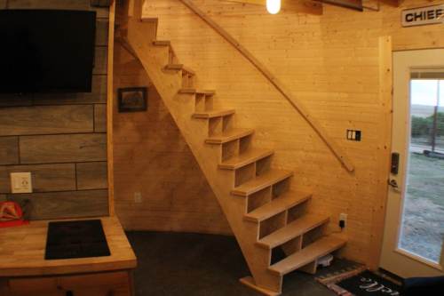 Interior view of a wooden staircase leading to an upper level, with a cozy, rustic design and a door to the outside.