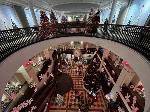 A festive atrium decorated with Christmas trees, snowflakes, and holiday lights, bustling with visitors.