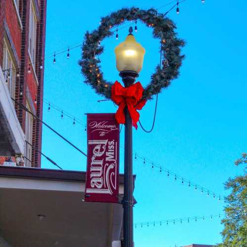 A festive street lamp adorned with a wreath and red bow, next to a welcome sign for "Laurel."