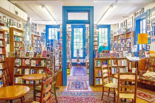 Cozy bookstore interior with bookshelves, seating areas, and large windows letting in natural light.