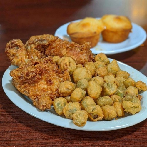 A plate of fried chicken, crispy fried okra, and two cornbread muffins on the side.