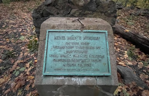 A weathered plaque on a stone commemorating the site where nine soldiers were killed in 1864.