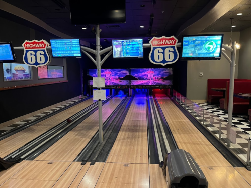 Bowling alley with neon lights, screens displaying scores, and a retro Highway 66 theme.