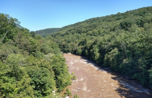 A winding river flows through lush green hills under a clear blue sky.