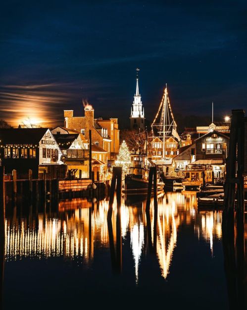 A picturesque waterfront scene at night, featuring illuminated buildings and reflections in the calm water.