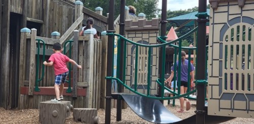 Children playing on a playground with climbing structures and slides, enjoying outdoor activities.