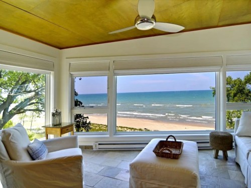 Cozy interior with white furniture and a stunning view of the beach and ocean through large windows.