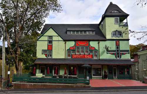 A colorful, multi-story building with a unique design, featuring the sign "Infinity Hall" and outdoor seating.