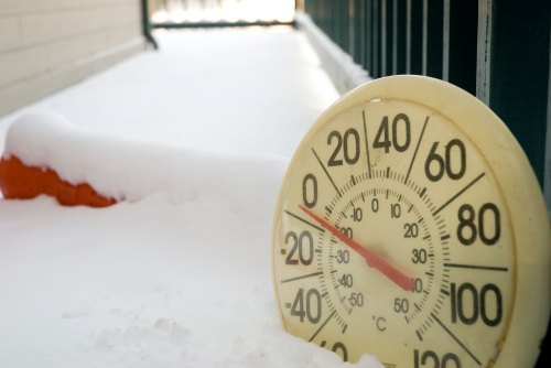 A thermometer partially buried in snow, showing a temperature around 20°F.