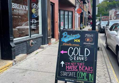 A chalkboard sign outside a bar advertises cold drinks and humorously mentions "maybe bears."