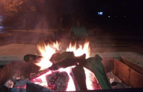 A cozy campfire with glowing flames and logs, set against a dark, nighttime background.