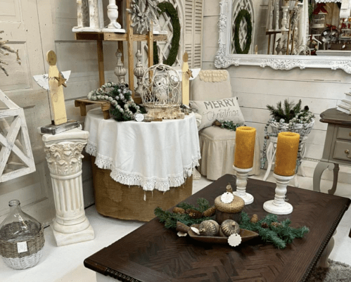 A cozy holiday display featuring candles, decorative items, and a festive table setting in a charming interior.