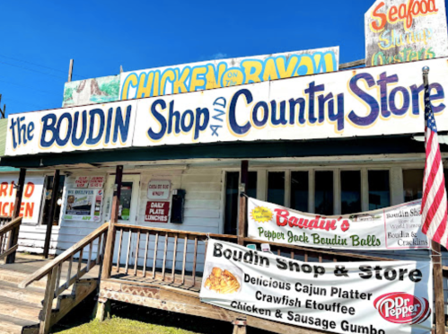 A colorful storefront of "The Boudin Shop and Country Store" with signs for Cajun food and an American flag.