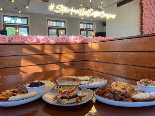 A table spread with various dishes, including a burger, sides, and a decorative backdrop with pink flowers and lights.