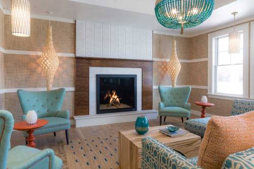 Cozy living room with a fireplace, teal armchairs, decorative lighting, and a wooden coffee table.