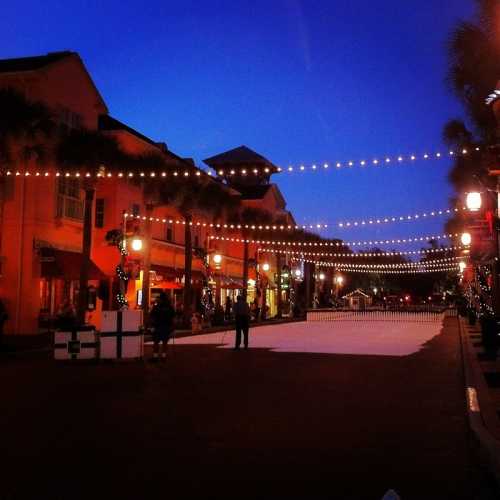 A charming street at dusk, lined with buildings and festive lights, creating a warm, inviting atmosphere.