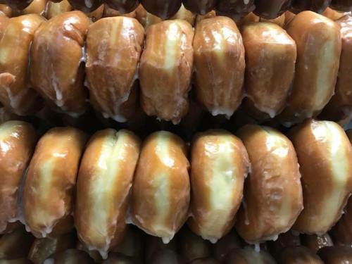 A close-up of glazed donuts stacked in rows, showcasing their shiny, golden-brown surfaces.