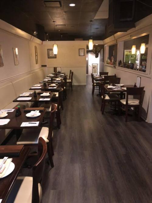 Interior of a restaurant with wooden tables set for dining, featuring a warm ambiance and dim lighting.