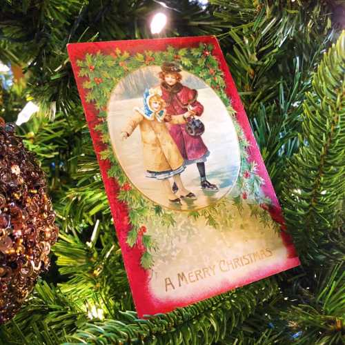 A vintage Christmas card featuring a snowy scene with a woman and child, surrounded by festive greenery.