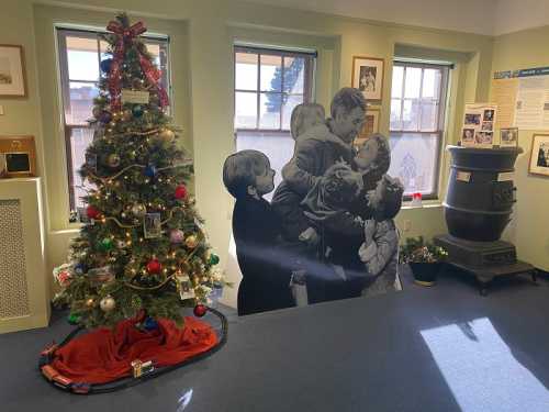 A decorated Christmas tree beside a vintage black-and-white cutout of a family joyfully celebrating together.