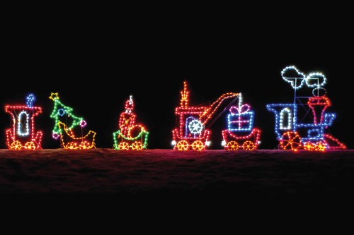 Colorful holiday lights depicting a train with festive decorations, including a Christmas tree and gifts, against a dark background.