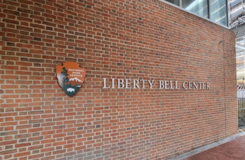 Sign on a brick wall reading "Liberty Bell Center" with a National Park Service emblem.