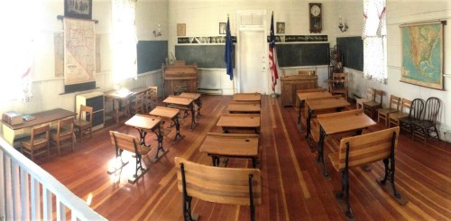 A vintage classroom with wooden desks, chalkboards, and maps, featuring a warm, nostalgic atmosphere.