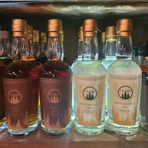 Bottles of maple rye and butterscotch rye whiskey lined up on a shelf, showcasing their distinct labels and colors.