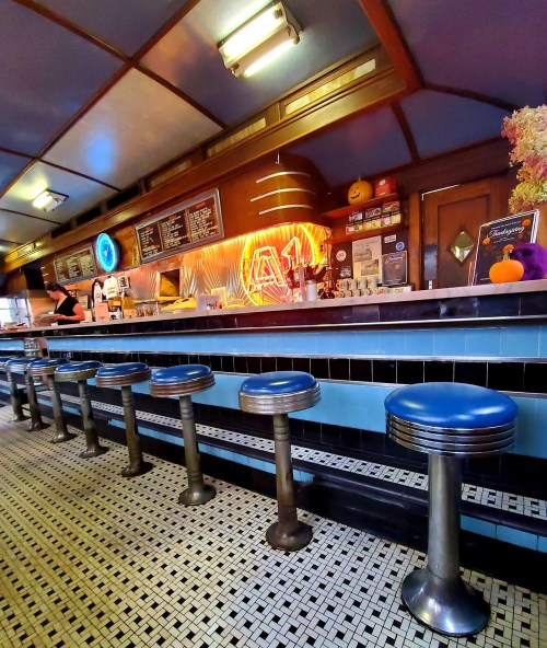 A retro diner interior featuring a long counter with chrome stools and a neon sign, creating a nostalgic atmosphere.