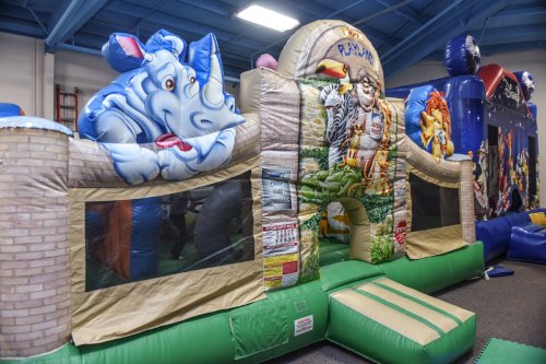 A colorful inflatable bounce house featuring cartoon animals and a playful design, set indoors.