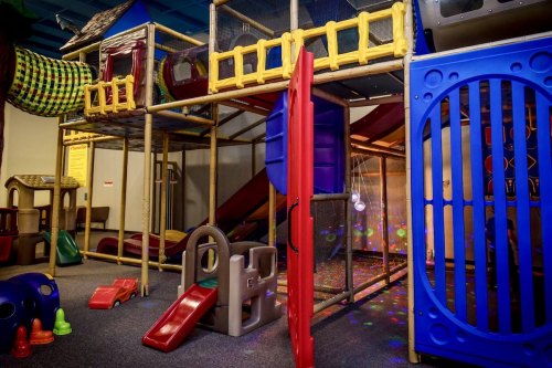 Colorful indoor playground with slides, climbing structures, and play equipment for children.