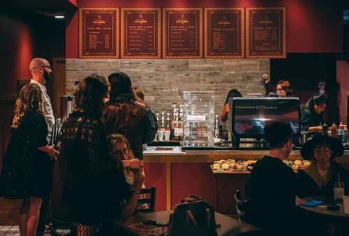 A cozy café scene with people chatting, a menu board, and a coffee counter in a warm, inviting atmosphere.