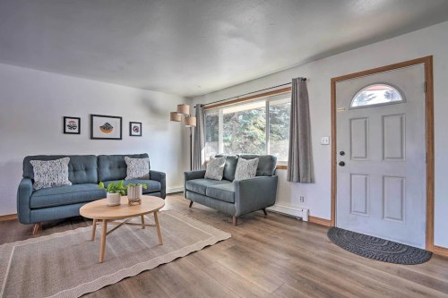 A cozy living room with two blue sofas, a round coffee table, and a large window letting in natural light.