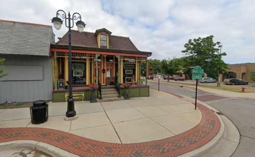 Colorful historic building on a corner, featuring decorative trim and a welcoming entrance, with street signs nearby.