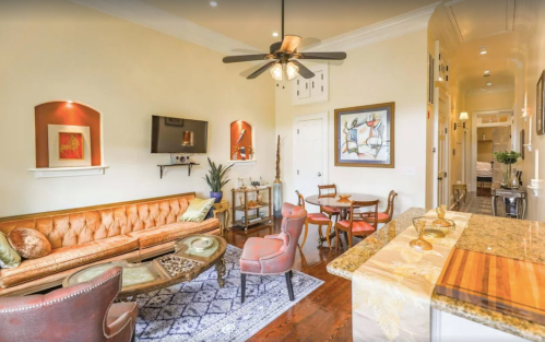 Cozy living room with a leather sofa, dining area, and elegant decor, featuring warm lighting and wooden accents.
