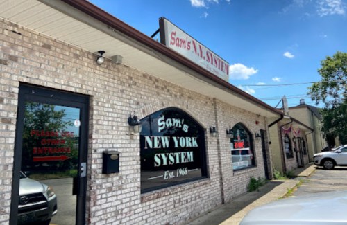 Exterior of Sam's New York System restaurant, featuring a brick facade and a sign with the establishment's name and year.